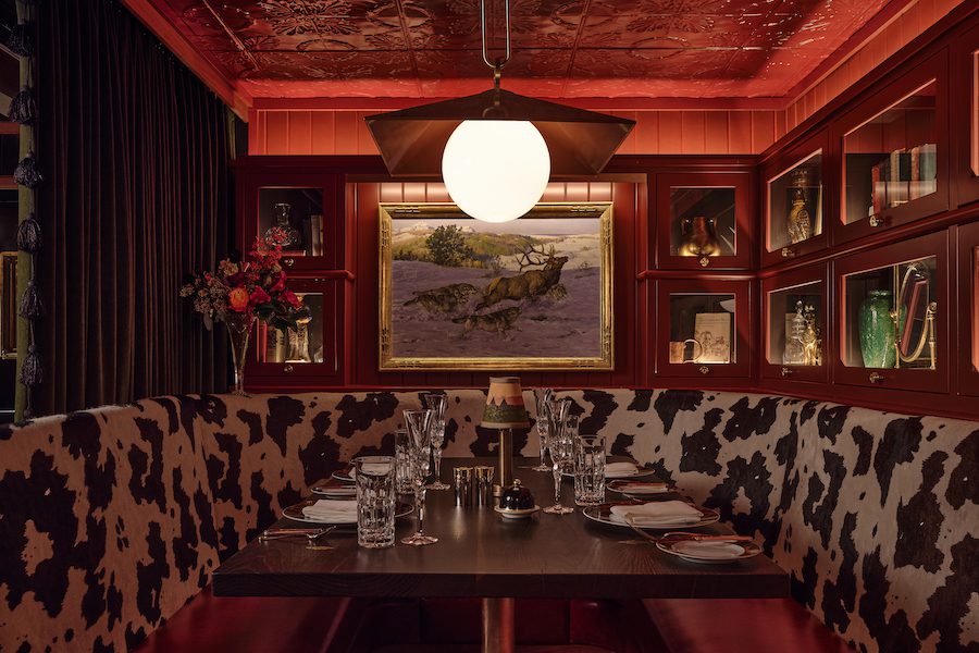 auric room social members club western speakeasy saloon with moody dark wallcoverings cow print banquette liquor cabinets